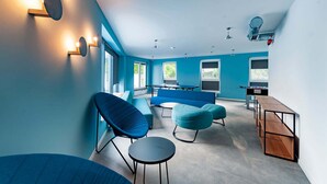 A modern room with a pool table, blue chairs, and a ping pong table.