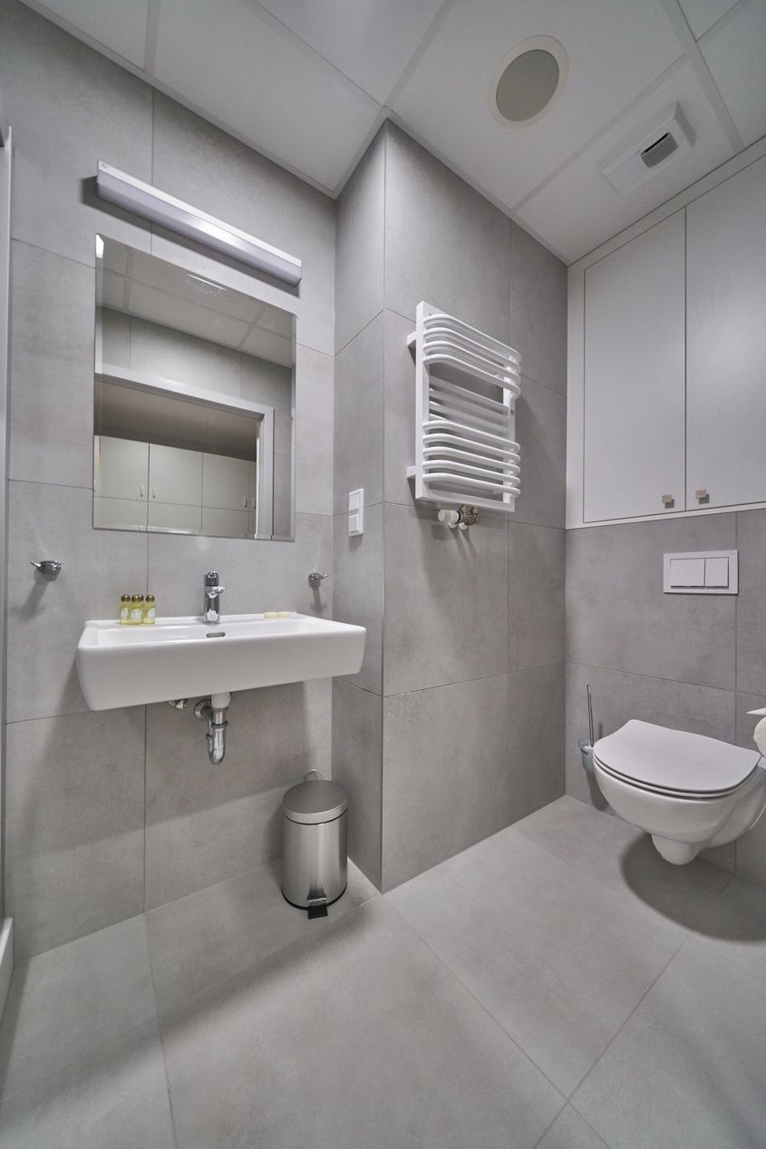 A modern bathroom with a white sink, mirror, and toilet.