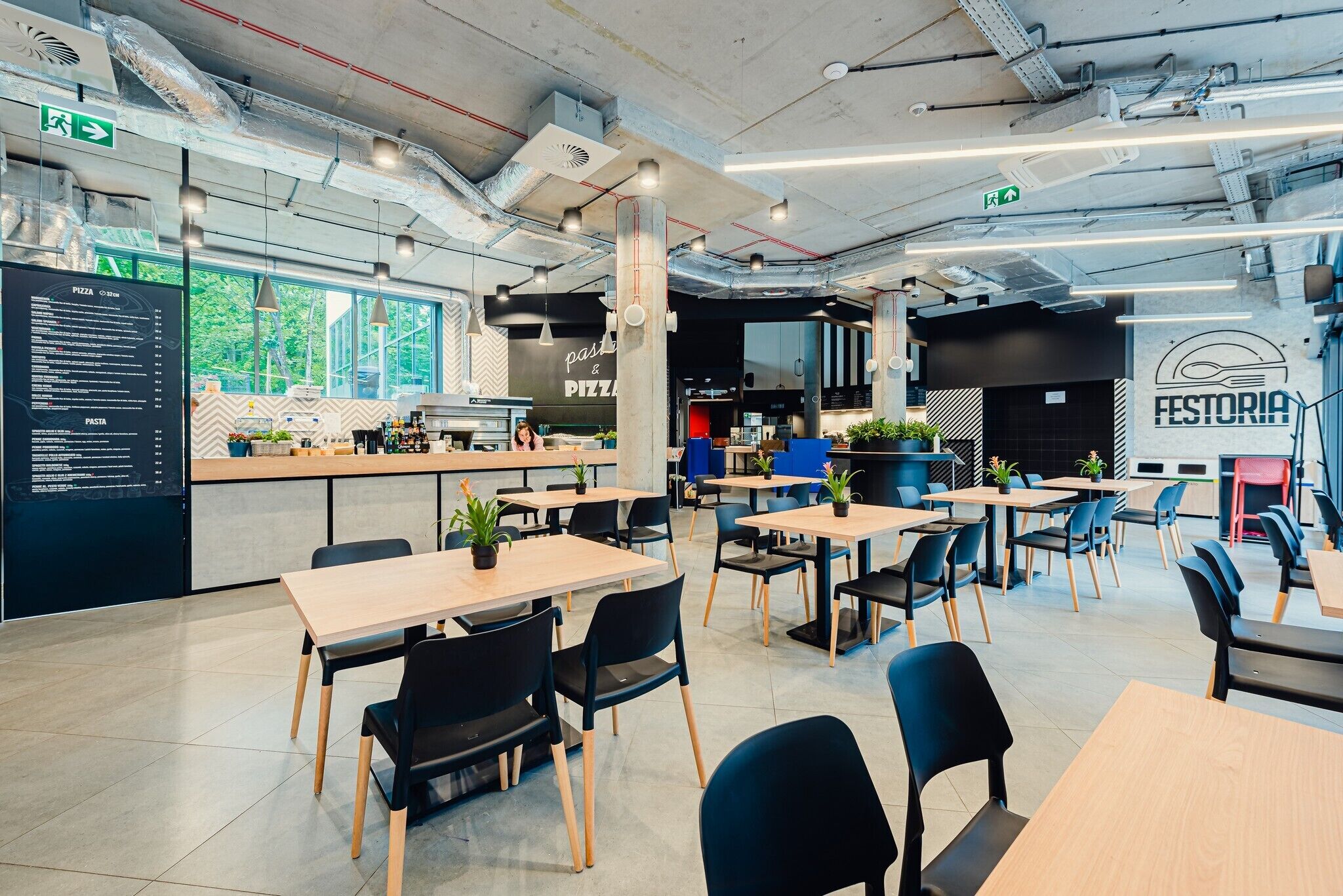 A modern restaurant with a menu board, tables, chairs, and a counter.