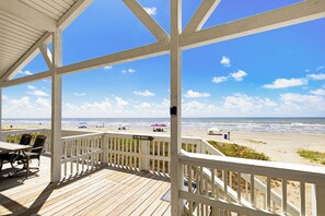 A wooden deck with a white railing overlooking a beach. - Steps to the Beach-Endless Views, pet friendly (Galveston)