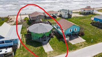 Vue aérienne d’une zone résidentielle côtière, avec des maisons, une plage et une vaste étendue d’eau.
