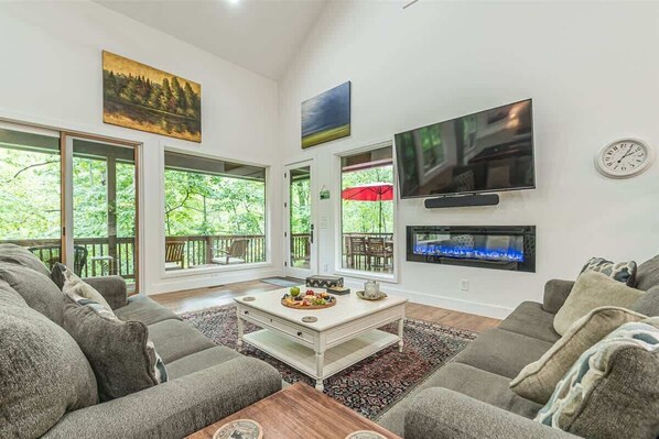 A living room with a fireplace, a flat-screen TV, and a dining area with a table set for four.