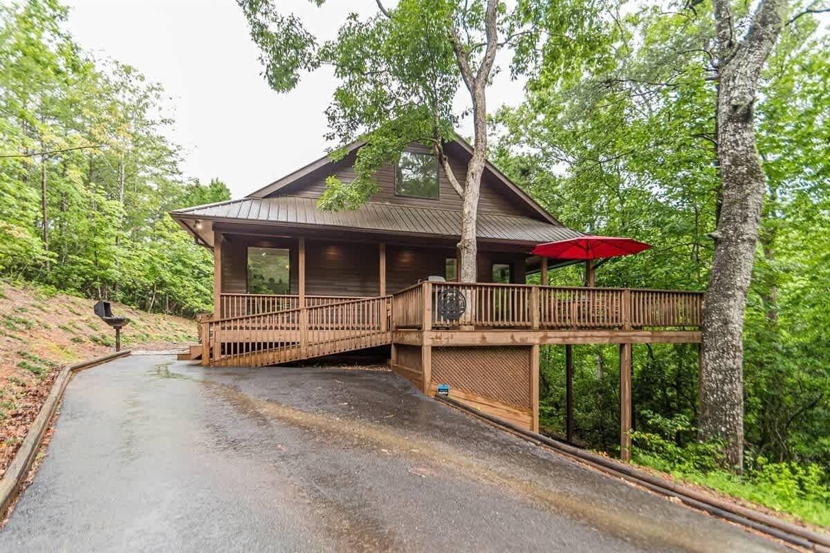 A wooden cabin with a covered deck and a red umbrella.