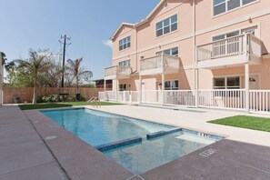 Um edifício residencial com vários andares, piscina, varandas e um gramado bem cuidado.