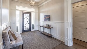 Un couloir avec un banc, une console, un tableau et une porte.