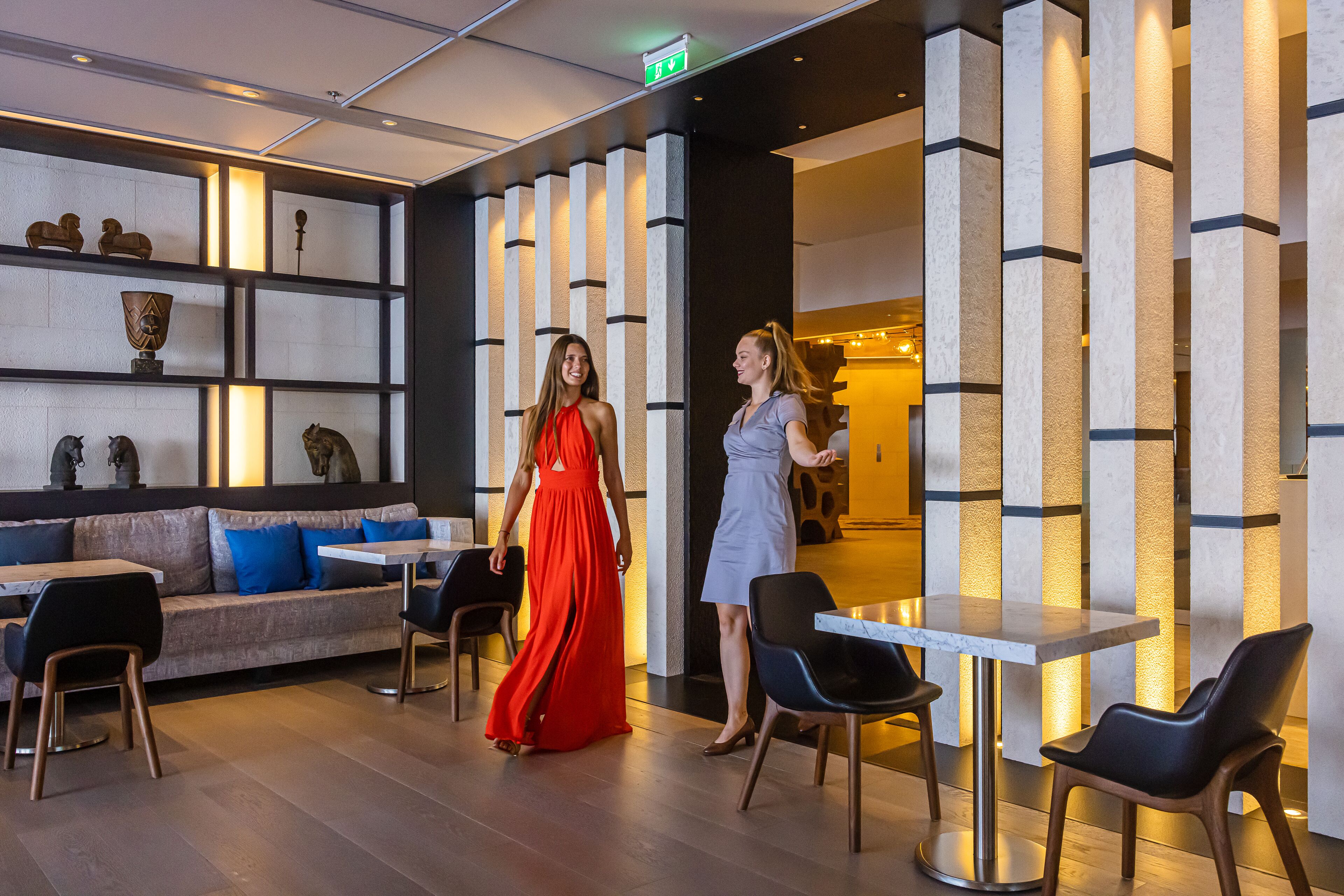 Un hall d’hôtel moderne avec un canapé, des fauteuils et un comptoir d’accueil.