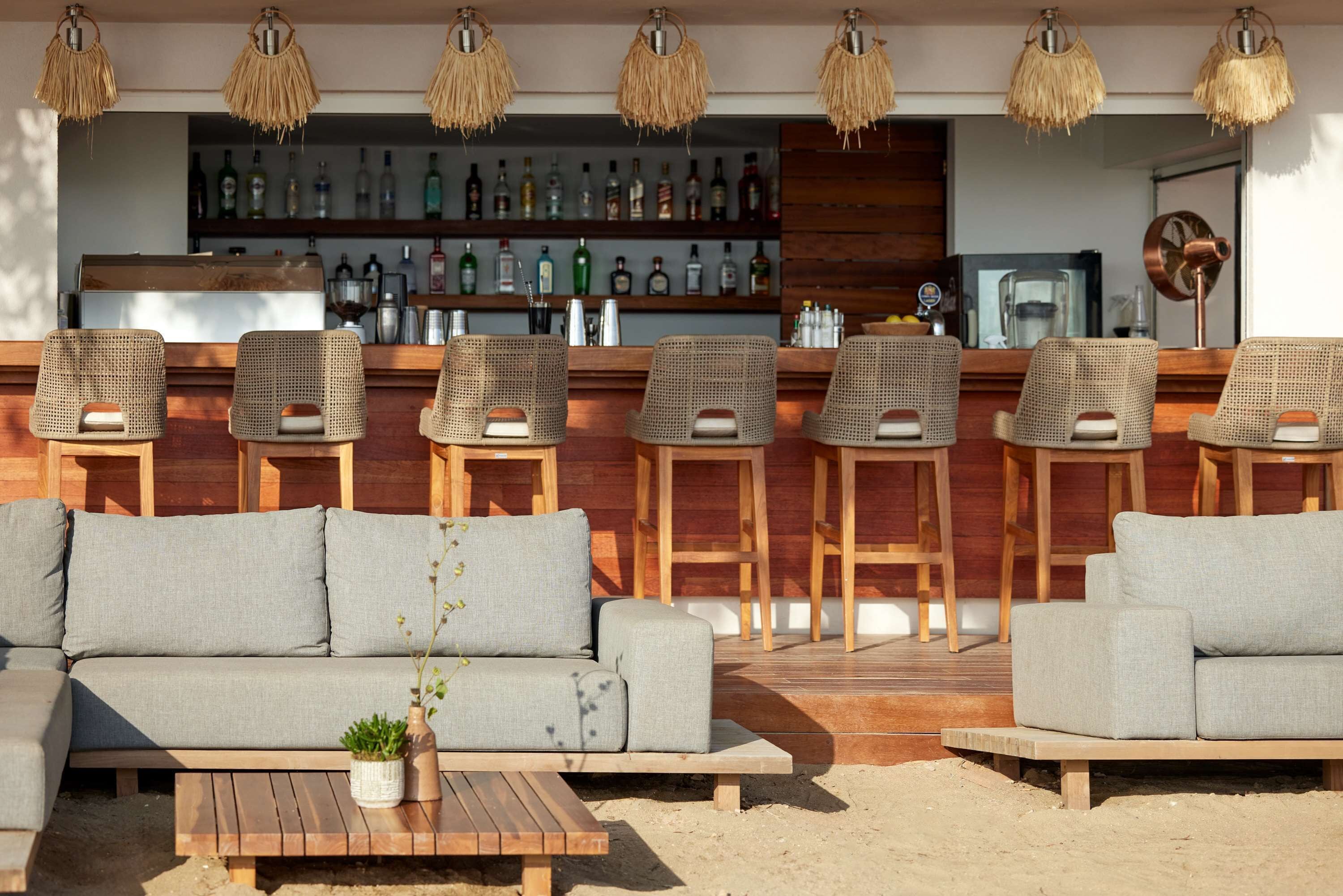 A bar area with wicker furniture and a variety of liquor bottles.