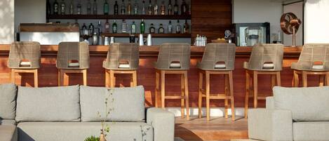 A bar area with wicker furniture and a variety of liquor bottles.