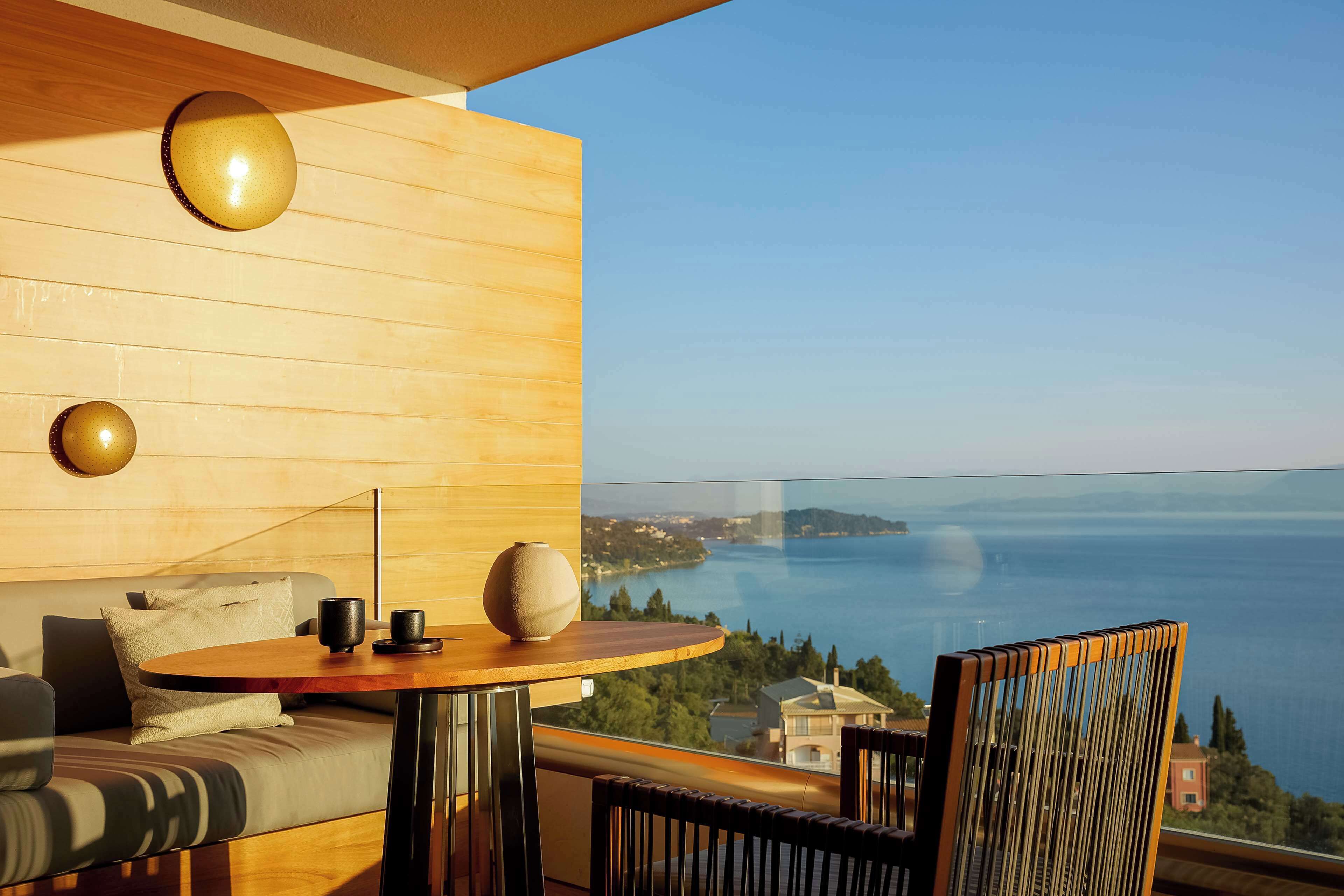 Habitación moderna con pared de madera, una mesa redonda con un florero y vistas a un lago.