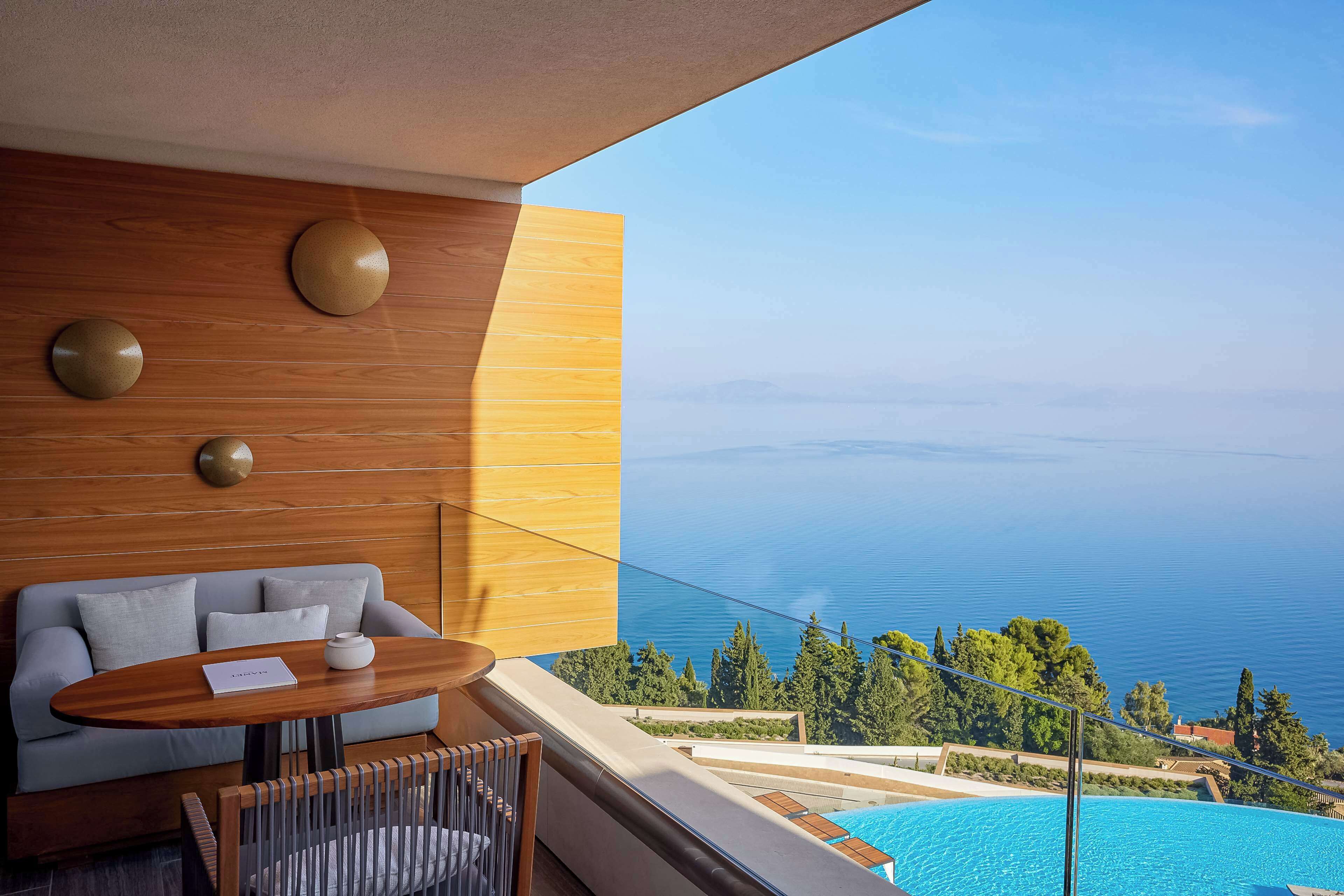 Ein modernes Zimmer mit einer Holzwand, einem Sofa, einem Tisch und Blick aufs Meer.
