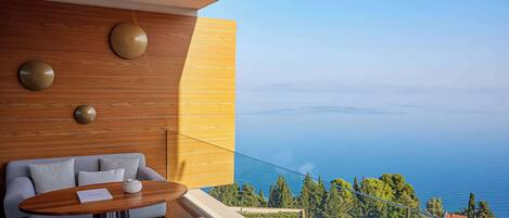 Ein modernes Zimmer mit einer Holzwand, einem Sofa, einem Tisch und Blick aufs Meer.