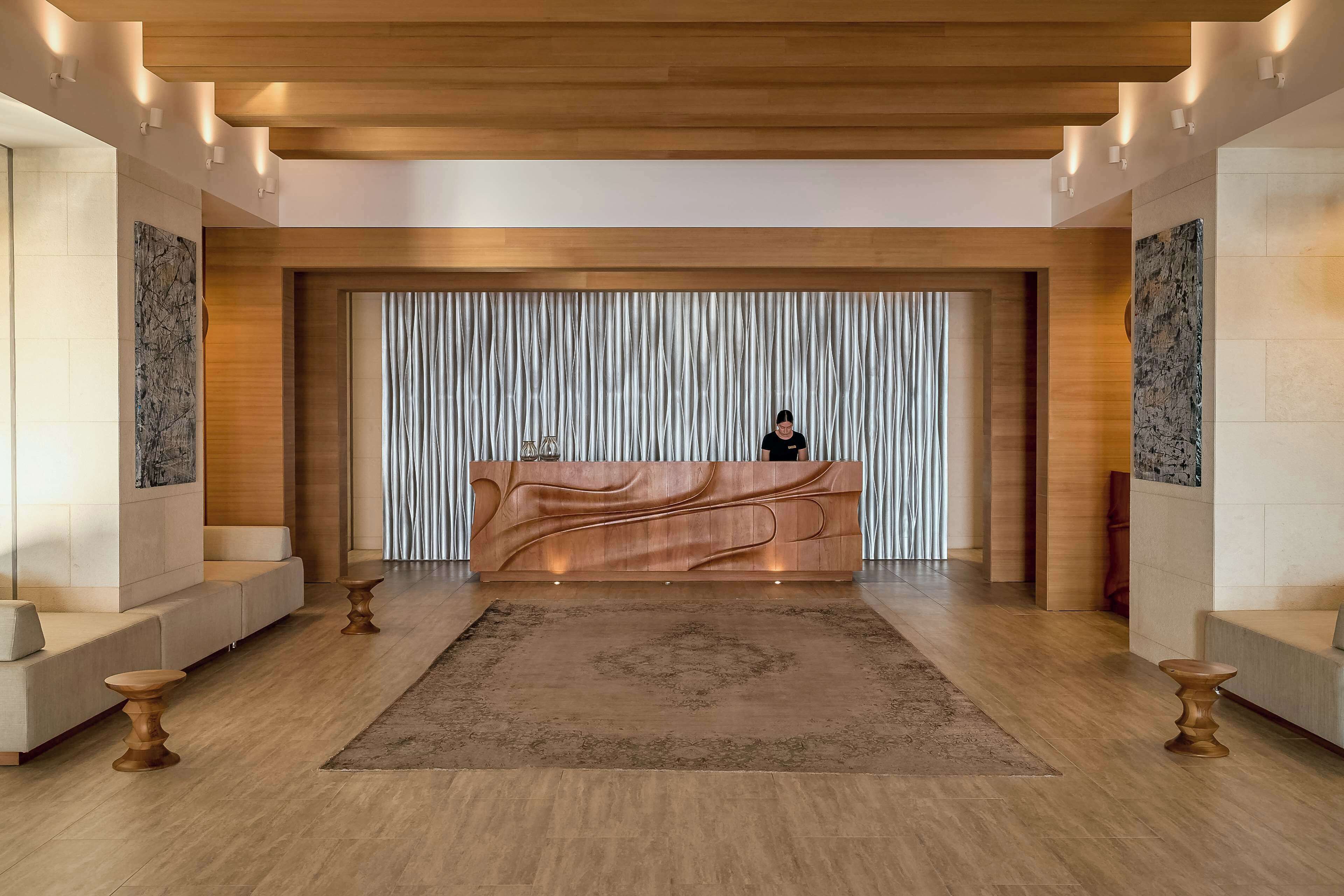 Una moderna zona de recepción con un mostrador de madera, un fondo estampado y una alfombra central.