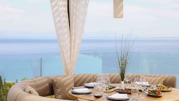 A dining table set with plates, glasses, and cutlery, overlooking a scenic view.