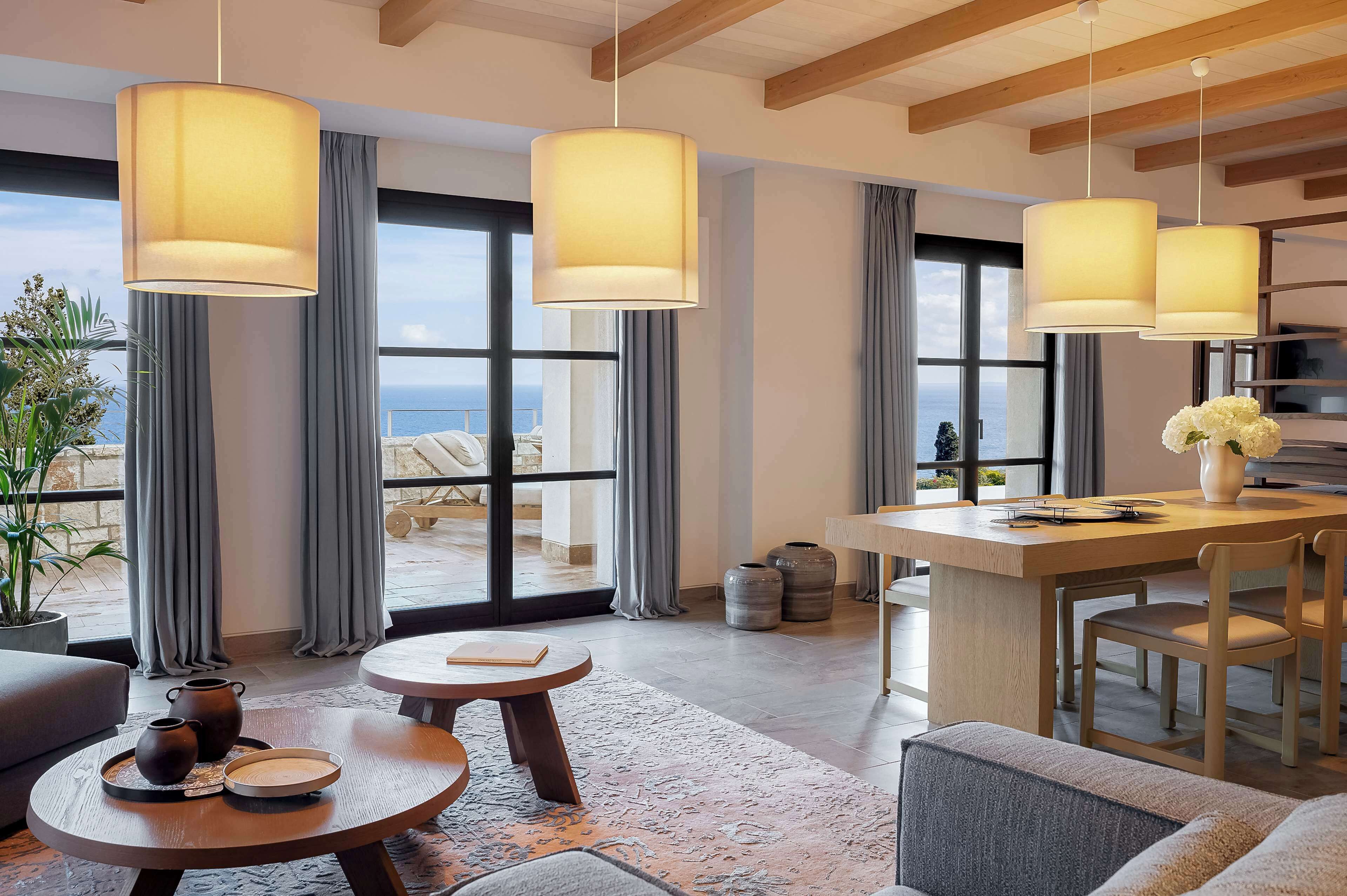 A modern hotel room with a large window, a wooden ceiling, and a dining area with a table and chairs.