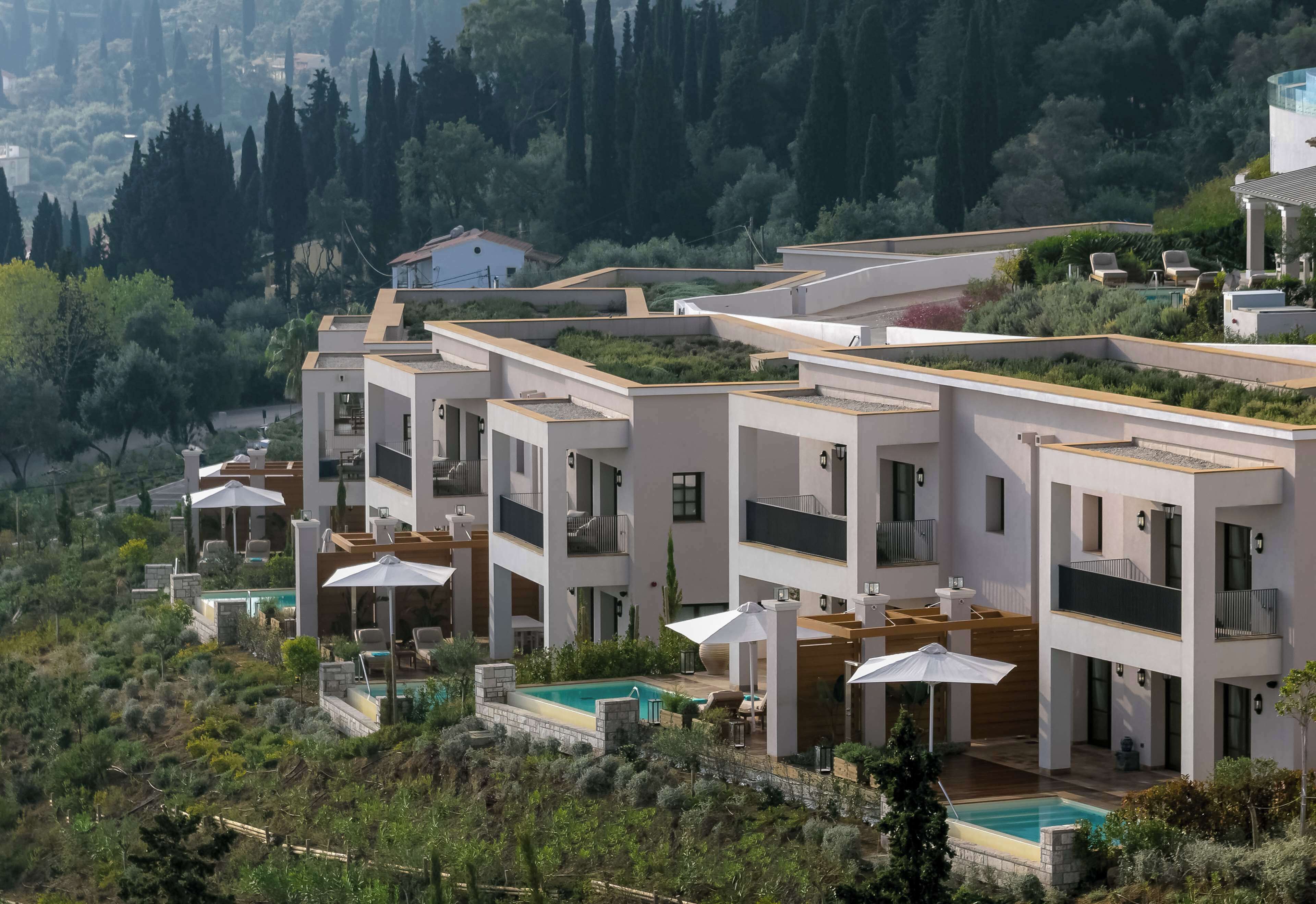 A modern multi-story residential building with a rooftop pool, outdoor seating areas, and lush greenery surrounding the property.