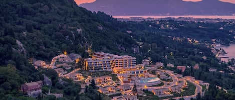 Un resort con varias edificaciones, una piscina y montañas al fondo.