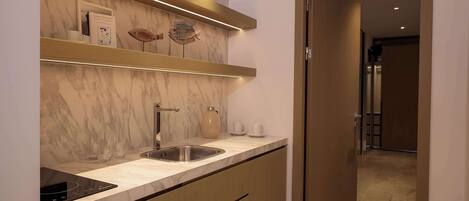 A modern kitchen with marble countertops, a built-in sink, and wooden cabinets.