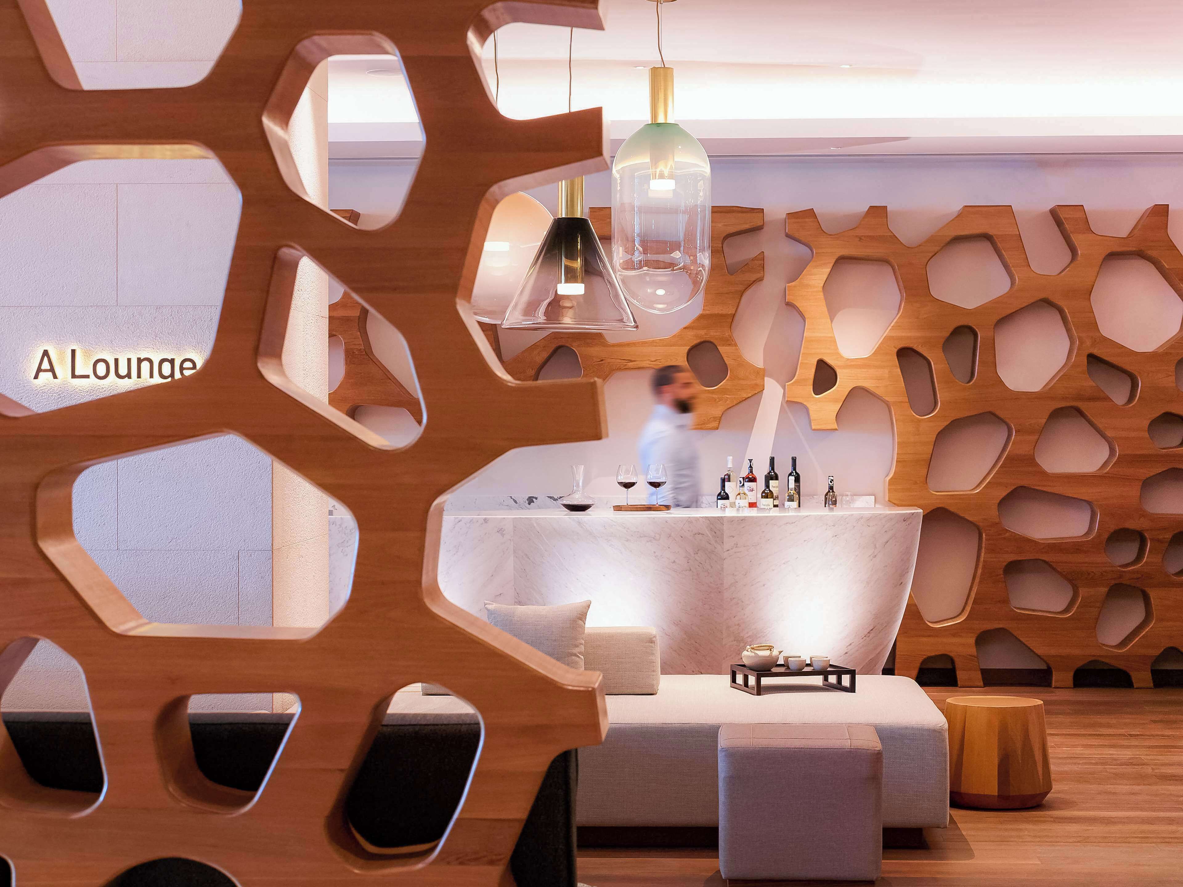 A lounge area with a wooden wall design, a marble counter with bottles, and seating.