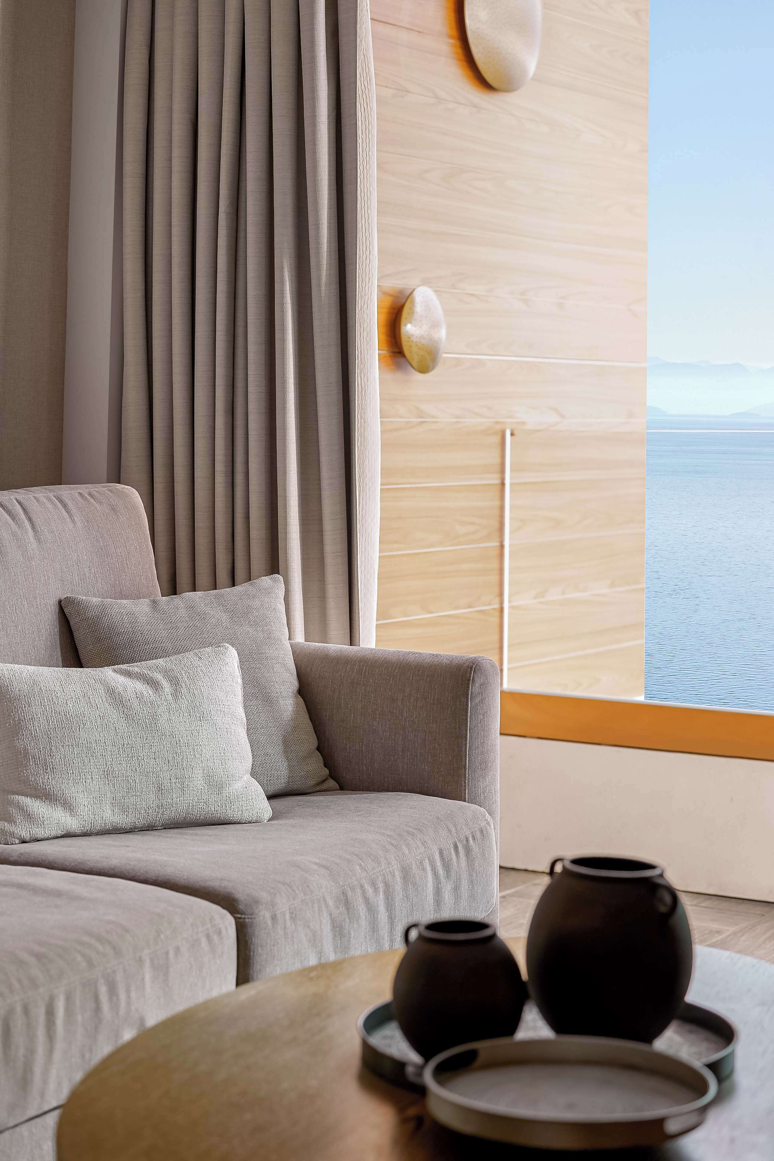 A modern living room with a sofa, cushions, a coffee table, and two vases.