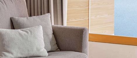 A modern living room with a sofa, cushions, a coffee table, and two vases.