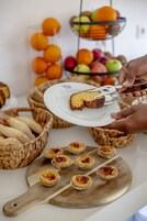 Una mesa con pasteles, un plato con una porción de pastel y panes en cestas.