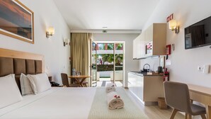 A hotel room with a bed, a desk, a chair, a TV, and a balcony with a view of the outdoors. - Hotel Rural Brícia du Mar (Lagoa)