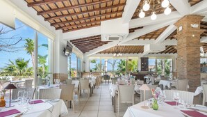 An outdoor dining area with tables set for two, featuring white tablecloths and wicker chairs. - Hotel Rural Brícia du Mar (Lagoa)
