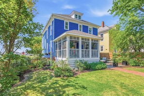 A two-story house with a covered porch and a well-maintained garden. - Stella Blu - Chesapeake Properties (Cape Charles)