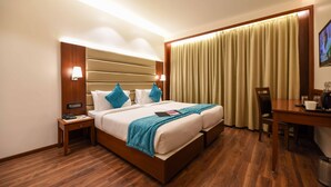 Une chambre d’hôtel avec un grand lit, des tables de chevet, un bureau et une chaise.