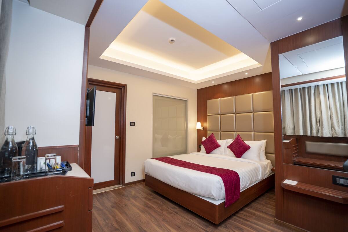 Ein modernes Hotelzimmer mit einem großen Bett, einem Holzkopfstück und einem Schreibtisch mit Spiegel.