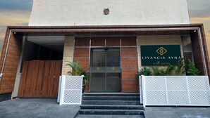 Un hôtel moderne doté d’une façade en verre remarquable, d’une entrée en bois et d’une enseigne indiquant « Livancia Ayra ».