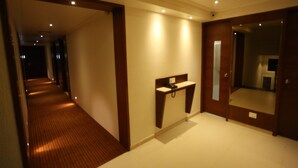Un couloir d’hôtel avec un plancher en bois, un comptoir de réception et un grand miroir accroché au mur.