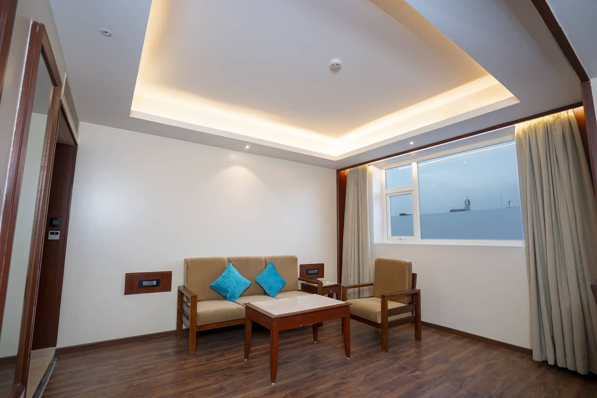 Ein modernes Zimmer mit einer Couch, zwei Sessel, einem kleinen Tisch und einem großen Fenster mit Meerblick.