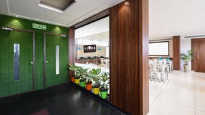 Un hall d’entrée agrémenté d’un mur végétal, de lambris en bois et de plantes en pot.
