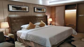 A hotel room with a large bed, two bedside lamps, a chair, and framed artwork on the wall.