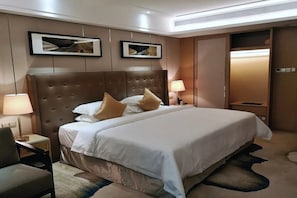 Habitación de hotel con una cama grande, dos lámparas de noche, una silla y cuadros en la pared.