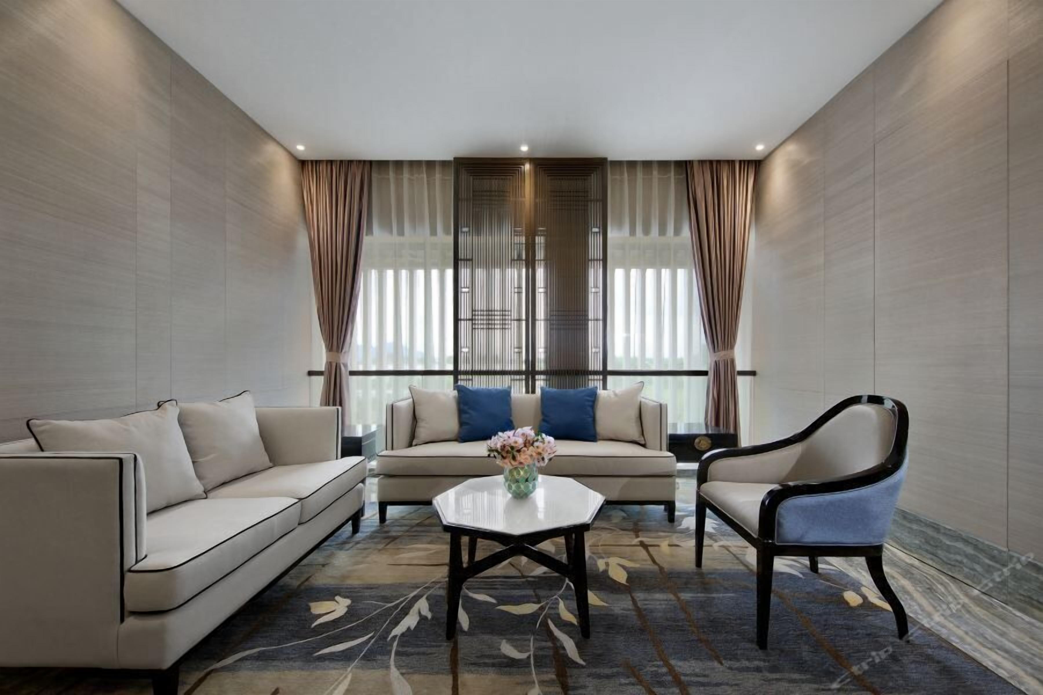 Una habitación de hotel moderna con sofá, sillón y una mesa de centro.