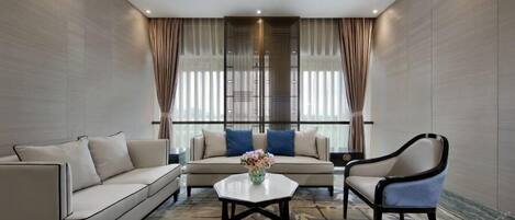 Una habitación de hotel moderna con sofá, sillón y una mesa de centro.