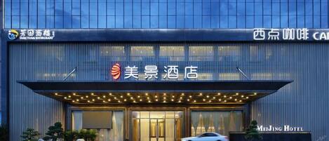 A modern hotel entrance with a large sign, a covered entrance, and a car parked in front.