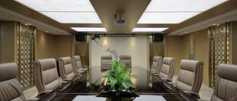 A conference room with a long table, multiple chairs, and a decorative plant in the center.