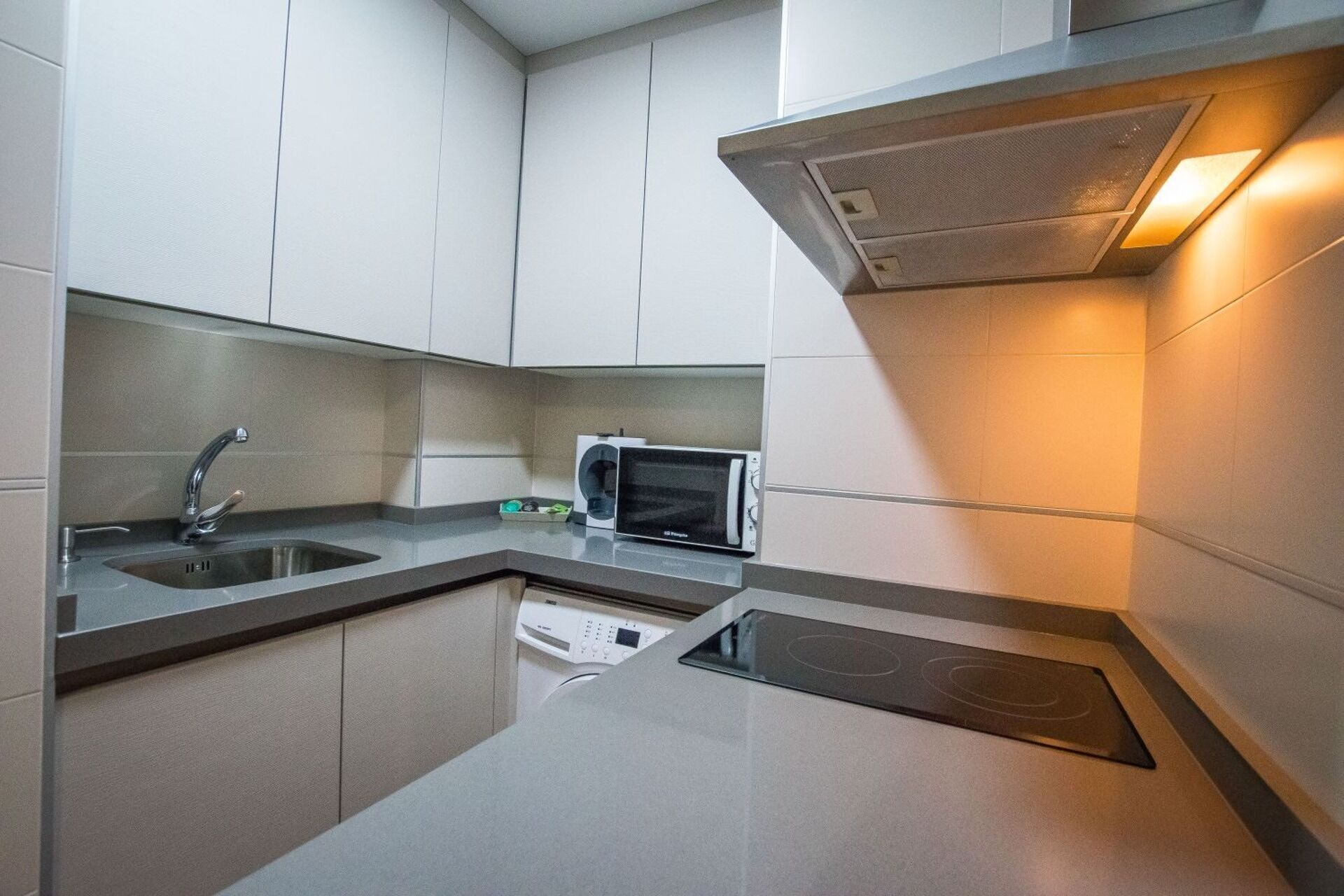 Cocina compacta con microondas integrado, pileta y cocina por inducción.