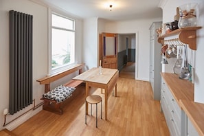 Una cocina con una mesa de madera, un banco y utensilios colgantes.