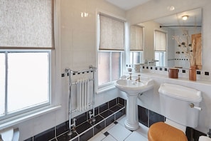 Un baño moderno con un ventanal amplio, un lavamanos pedestal, un inodoro y un espejo.