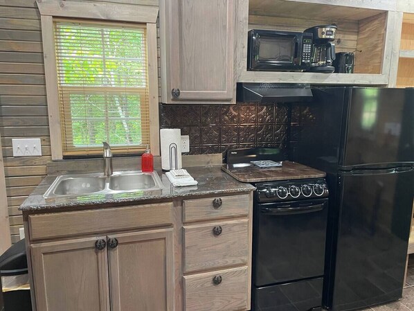 A kitchen with a sink, stove, microwave, and coffee maker.