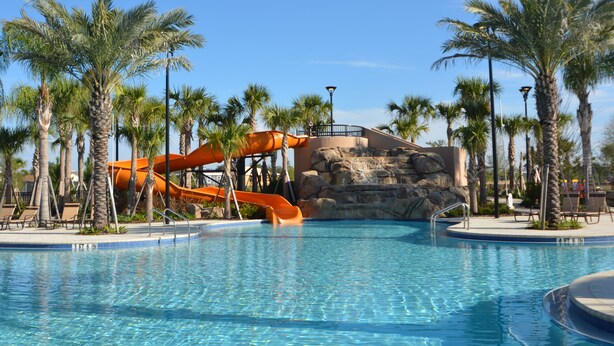 A pool with a water slide, palm trees, and lounge chairs. - Solterra Resort Pool & Spa, Games Room, Lake View & Extensive Resort Amenities (Davenport)