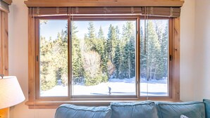 A room with a large window overlooking a snowy forest. - Beautiful Mountain 2 Bedroom Ski-In/Ski-Out in Ski Trails by RedAwning Save 10% on 3 Nights, 15% on 5 Nights! (Truckee)