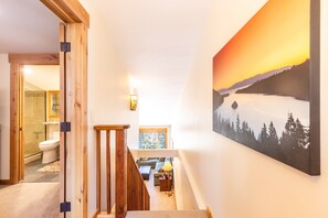 Eine Treppe führt zu einem Wohnbereich, in dem ein Gemälde einer verschneiten Landschaft zu sehen ist.