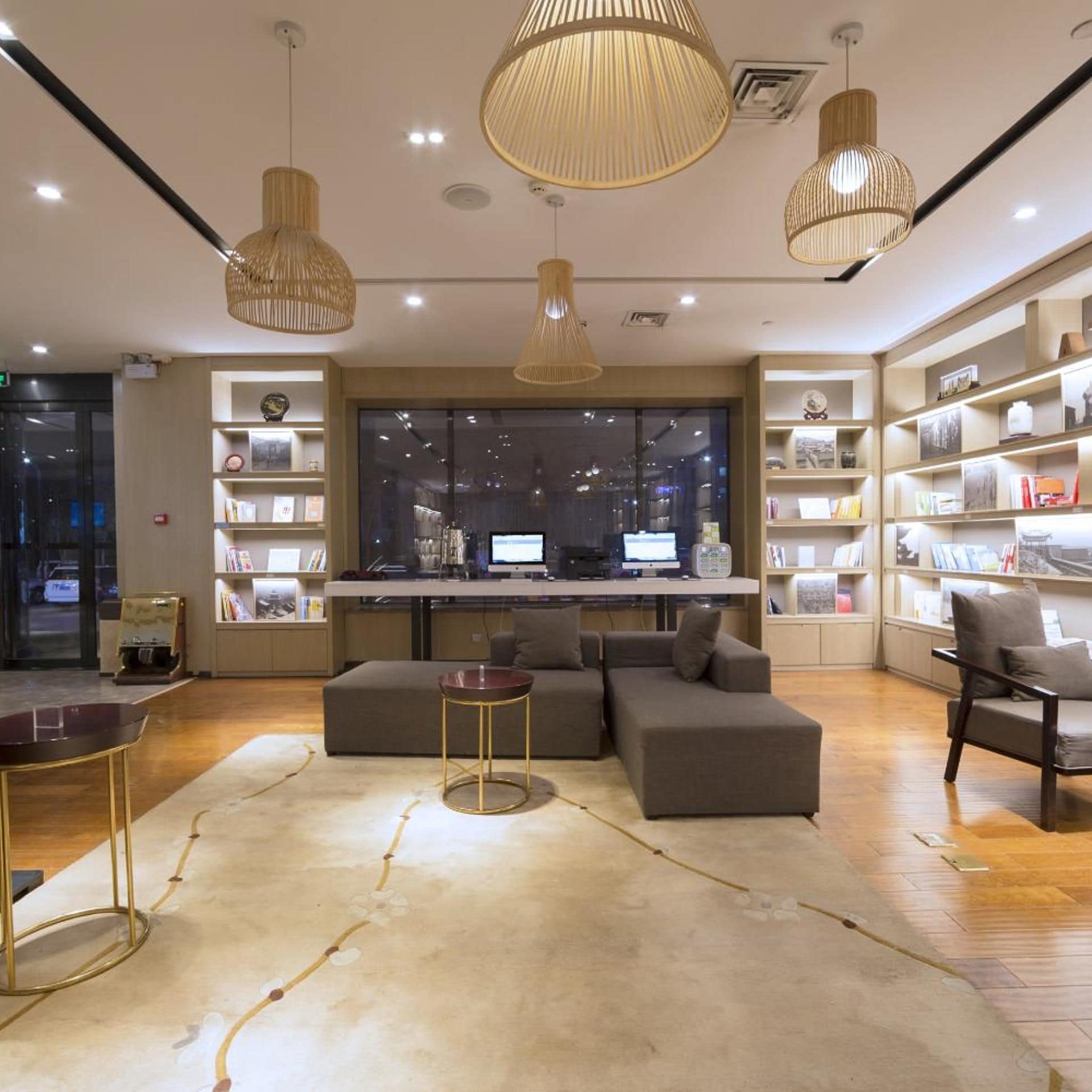 A modern interior with a seating area, bookshelves, and a large window.