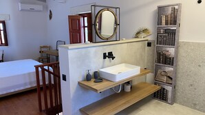 Ein Badezimmer mit einem Holzkosmetikschrank, einem weißen Waschbecken und einem Regal mit Büchern.