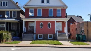 A two-story residential building with a red facade, white trim, and a gabled roof.